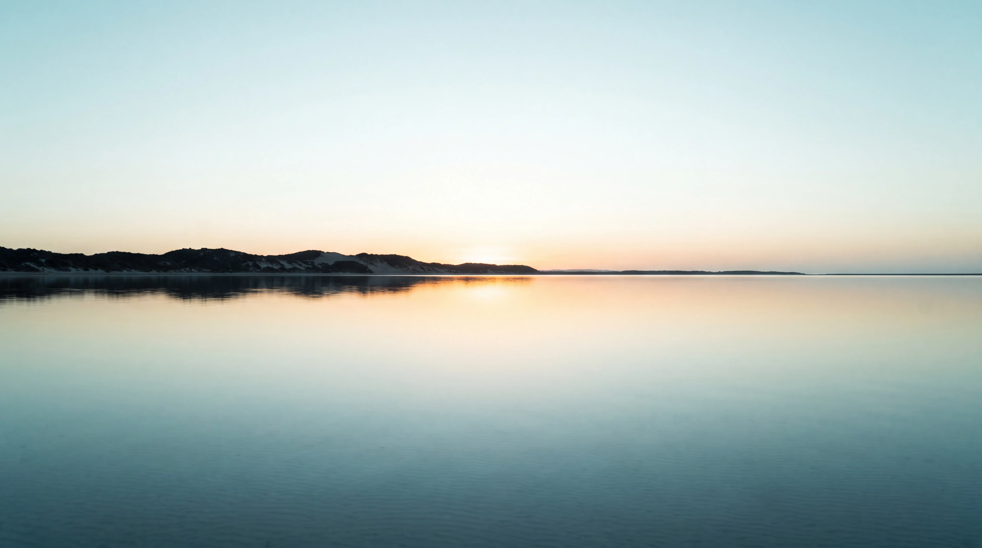 Still estuary water reflecting the first light of dawn