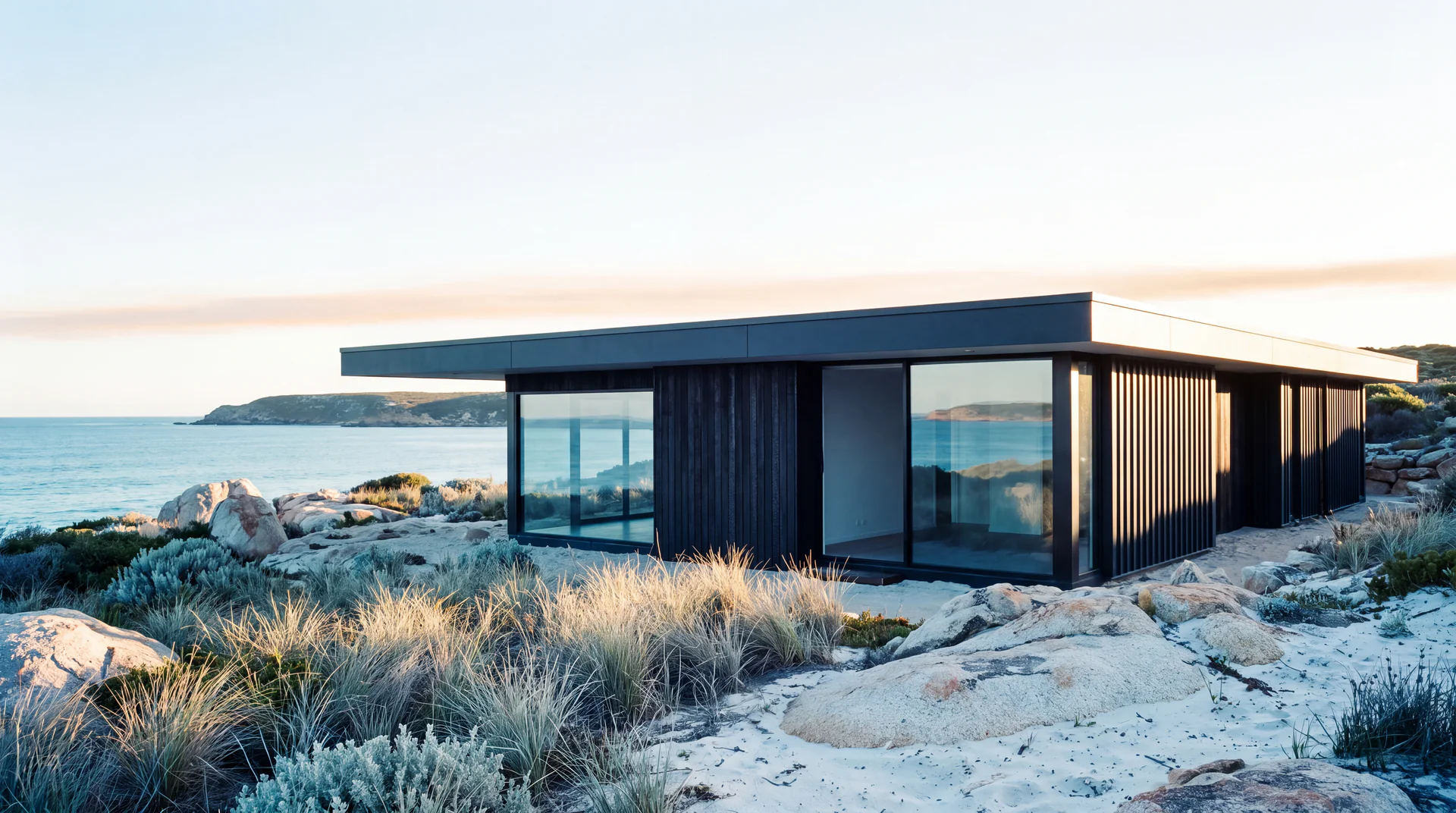 Dark-clad coastal home in clear morning light above the sea